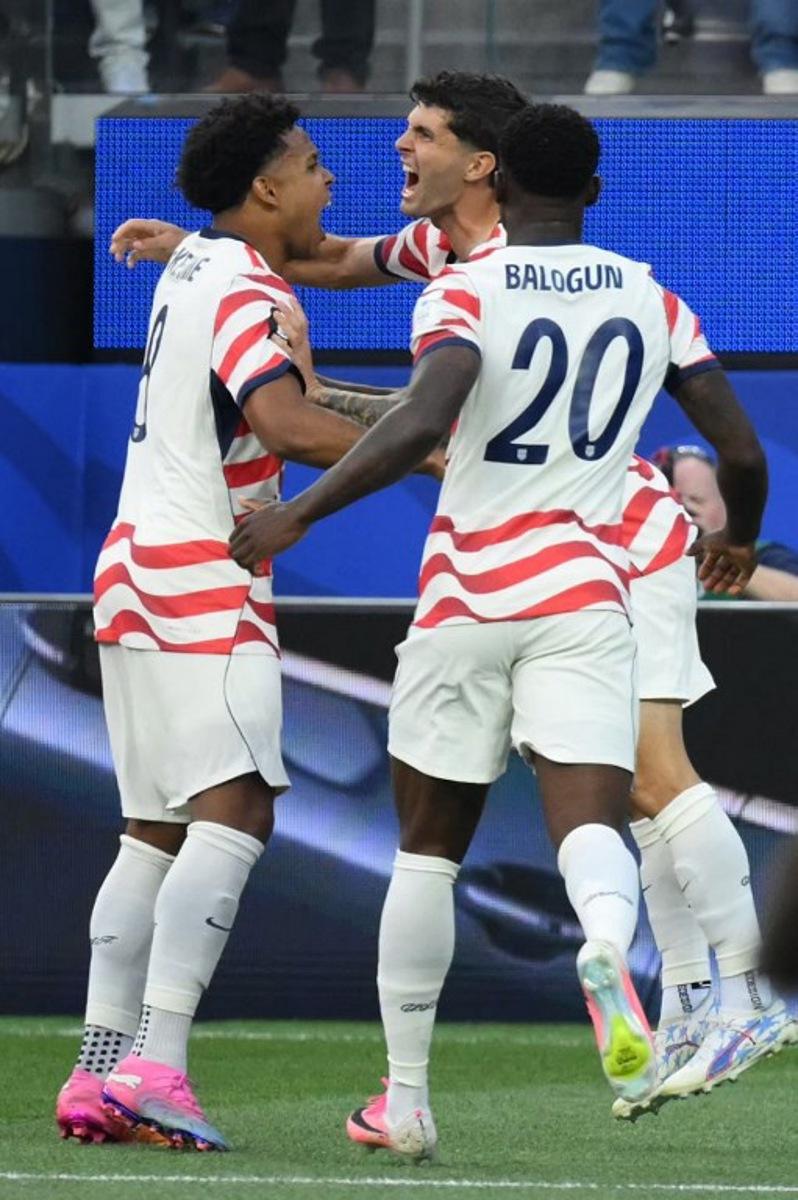 US forward #10 Christian Pulisic (C) celebrates with teammates after his team's first goal scored on own goal by Paraguay's midfielder #16 Damian Bobadilla (unseen) during the 2026 World Cup Group D football match between USA and Paraguay at the Los Angeles Stadium in Inglewood on June 12, 2026.  Patrick T. Fallon / AFP