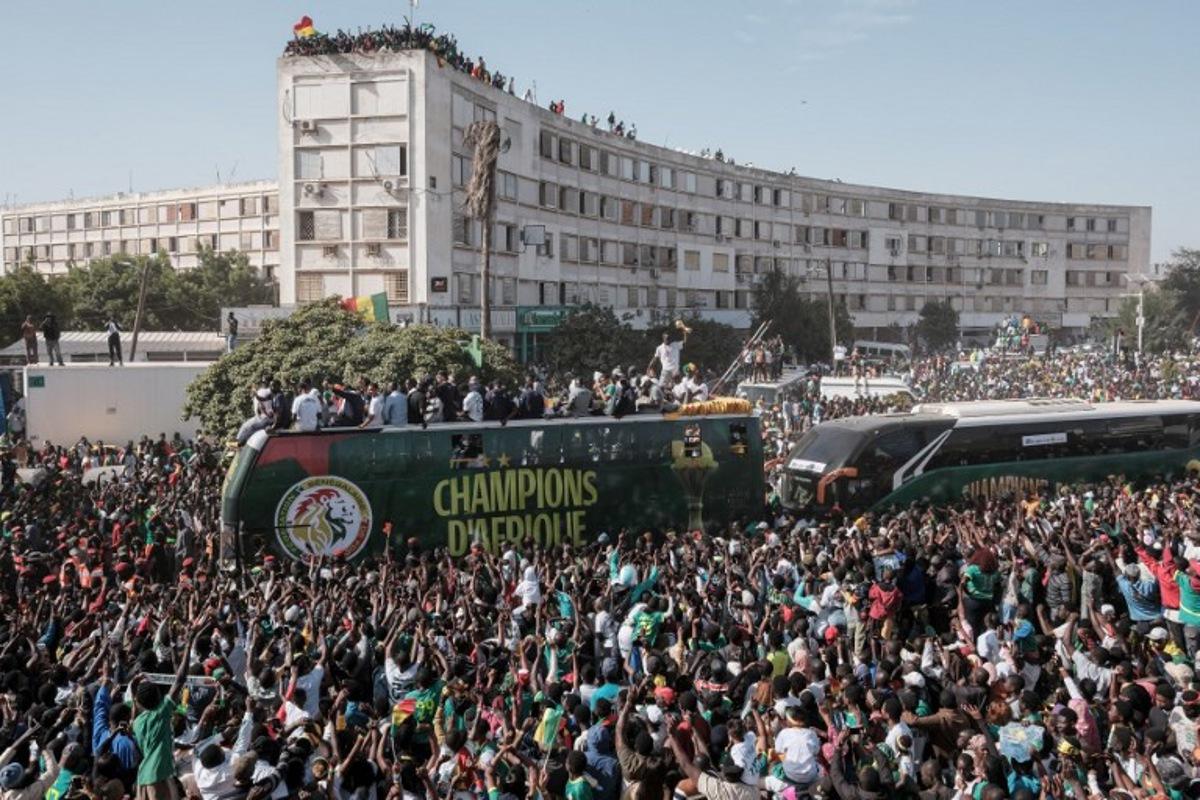 (FILES) Supporters cheer as the Senegalese football players ride on a bus during a trophy parade in the streets of Dakar on January 20, 2026 as they celebrate Senegal winning the Africa Cup of Nations (CAN) that was hosted in Morocco. Senegal football fans slammed AFCON'S decision to strip the country of its Africa Cup of Nations title and give it to Morocco, calling the move a "disgrace for Africa" as they woke up to the news Wednesday. Gora Ndiaye, a resident of Dakar who works as a chauffeur, told AFP he felt like he had "been hit over the head" when he heard the news on the radio. The Confederation of African Football (CAF) sensationally stripped Senegal of their title late Tuesday, citing regulations about leaving the field, which members did during the end of the final two months ago.  GUY PETERSON / AFP