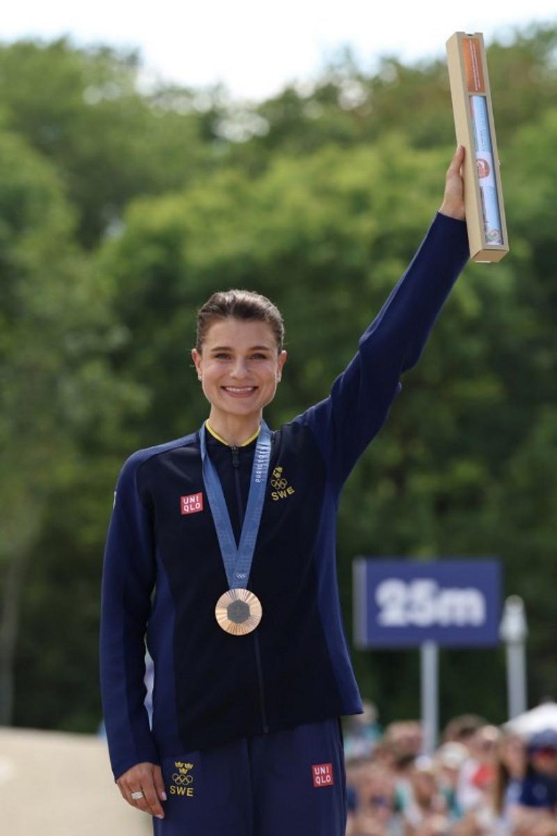 Bronze medallist Sweden's Jenny Rissveds celebrates on the podium after taking third place the women's cross-country mountain biking event during the Paris 2024 Olympic Games in Elancourt Hill venue in Elancourt, on July 28, 2024.   Emmanuel DUNAND / AFP
