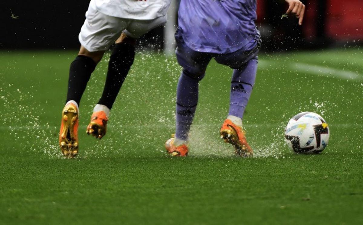 Players run on a waterlogged pitch during the Spanish league football match between Sevilla FC and Real Madrid CF at the Ramon Sanchez Pizjuan stadium in Seville on May 27, 2023.  CRISTINA QUICLER / AFP