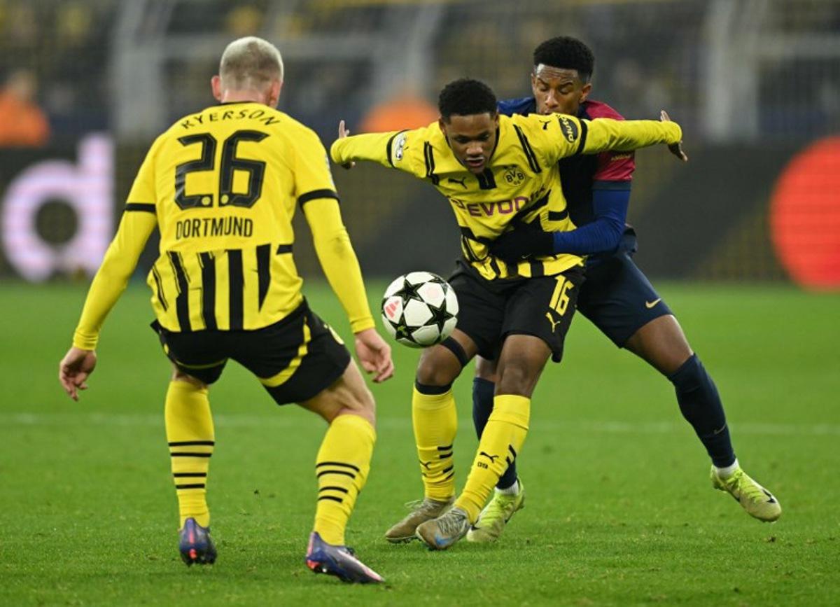 Borussia Dortmund's Belgian forward #16 Julien Duranville (C), Borussia Dortmund's Norwegian defender #26 Julian Ryerson (L) and Barcelona's Spanish defender #03 Alex Balde vie for the ball during the UEFA Champions League football match between Borussia Dortmund and FC Barcelona in Dortmund, western Germany on December 11, 2024.  INA FASSBENDER / AFP