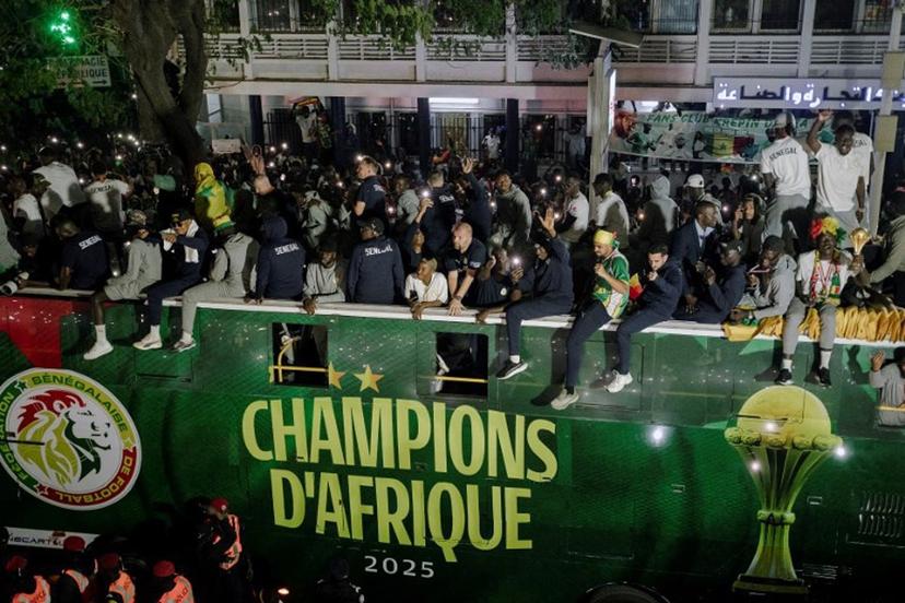 Senegal's Football Team players celebrate winning the Africa Cup of Nations (CAN) atop an open bus during a trophy parade in the streets of Dakar on January 20, 2026. Senegal's national football team, crowned African Nations champion thanks to its victory over Morocco on January 18 in Rabat after a high-octane final, landed late on January 19 night back home, where it was warmly welcomed off the plane by the Senegalese head of state and his government. Carmen Abd Ali / AFP