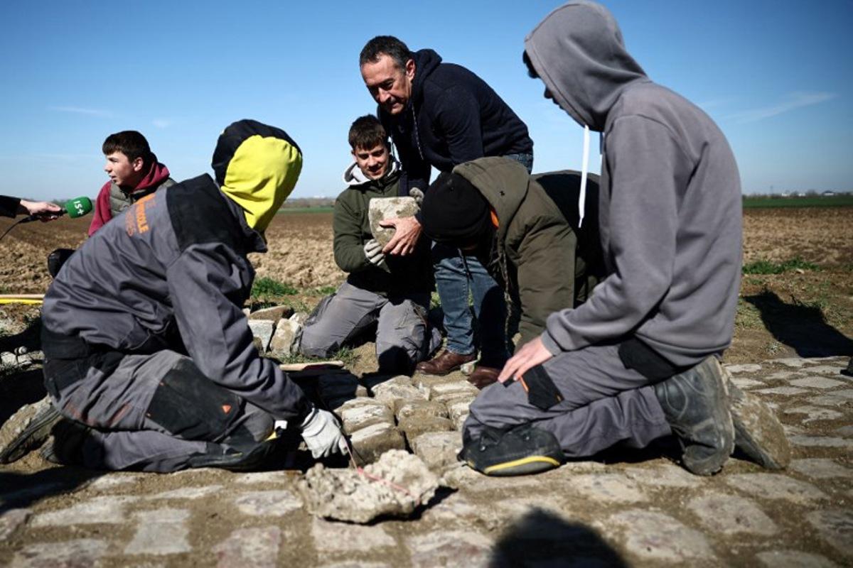 Workers repair cobblestones on the route of the Paris-Roubaix cycling race, in presence of race director Thierry Gouvenou (C), near Arenberg, on April 4, 2023, ahead of this week-end's women and men races.  Anne-Christine POUJOULAT / AFP
