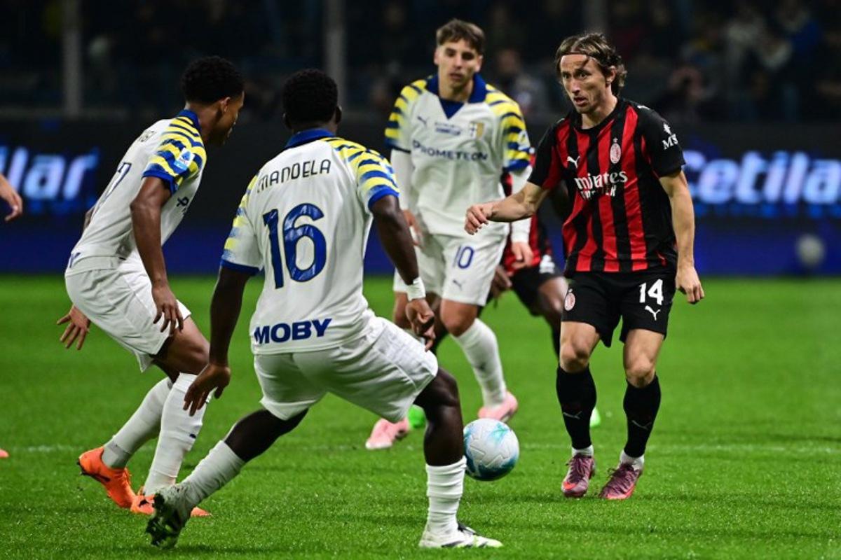 AC Milan's Croatian midfielder #14 Luka Modric (R) fights for the ball with Parma's Belgian midfielder #16 Mandela Keita (2nd L) during the Italian Serie A football match between Parma and AC Milan at the San Siro Stadium in Parma, northern Italy, on November 8, 2025.  Piero CRUCIATTI / AFP