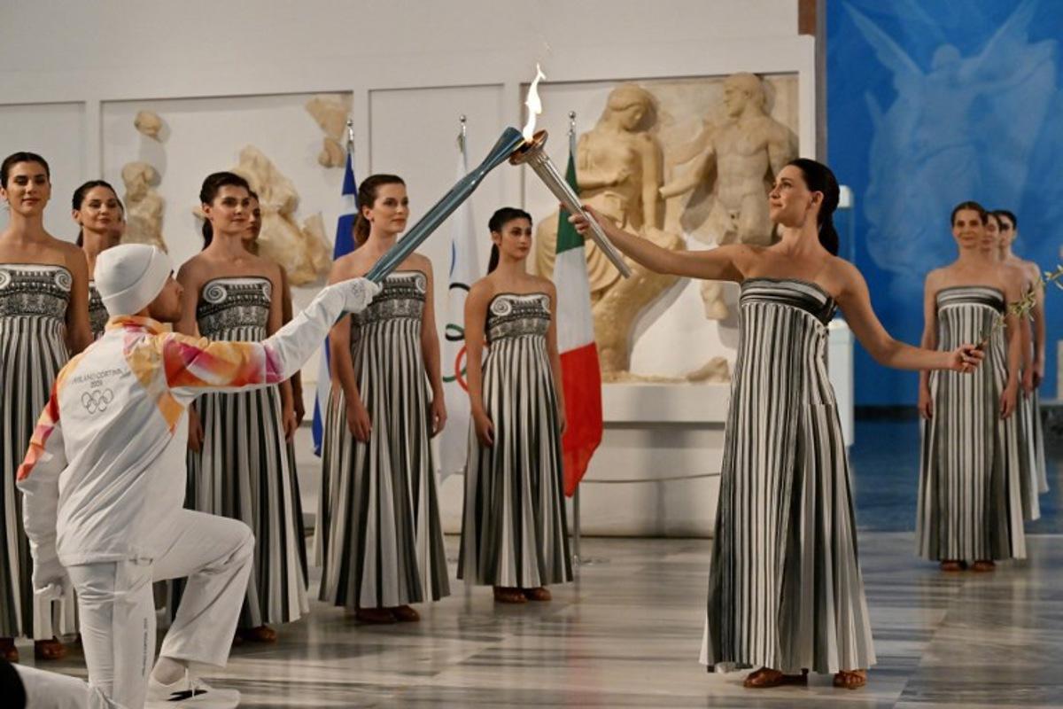 Greek actress Mary Mina (R), playing the role of the High Priestess, takes part in the flame lighting ceremony of the Olympic flame, for the Olympic Winter Games Milano Cortina 2026, at the Museum of ancient Olympia, in Olympia on November 26, 2025.  Aris MESSINIS / AFP