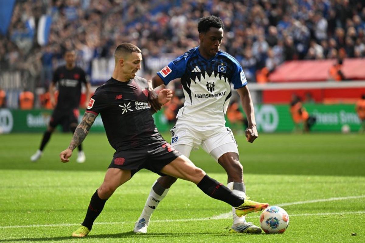 Bayer Leverkusen's Spanish defender #20 Alejandro Grimaldo and Hamburg's Belgian-Congolese midfielder #06 Albert Sambi Lokonga vie for the ball during the German first division Bundesliga football match between Bayer Leverkusen and Hamburger SV (HSV) in Leverkusen, western Germany, on May 16, 2026.  INA FASSBENDER / AFP