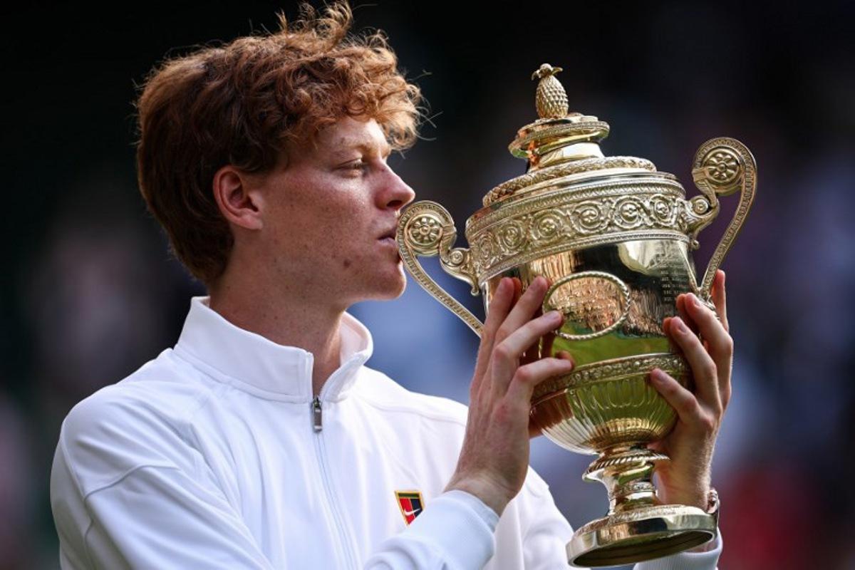 Italy's Jannik Sinner kisses the winner's trophy as he poses for pictures following his victory against Spain's Carlos Alcaraz at the end of their men's singles final tennis match on the fourteenth day of the 2025 Wimbledon Championships at The All England Lawn Tennis and Croquet Club in Wimbledon, southwest London, on July 13, 2025.  HENRY NICHOLLS / AFP