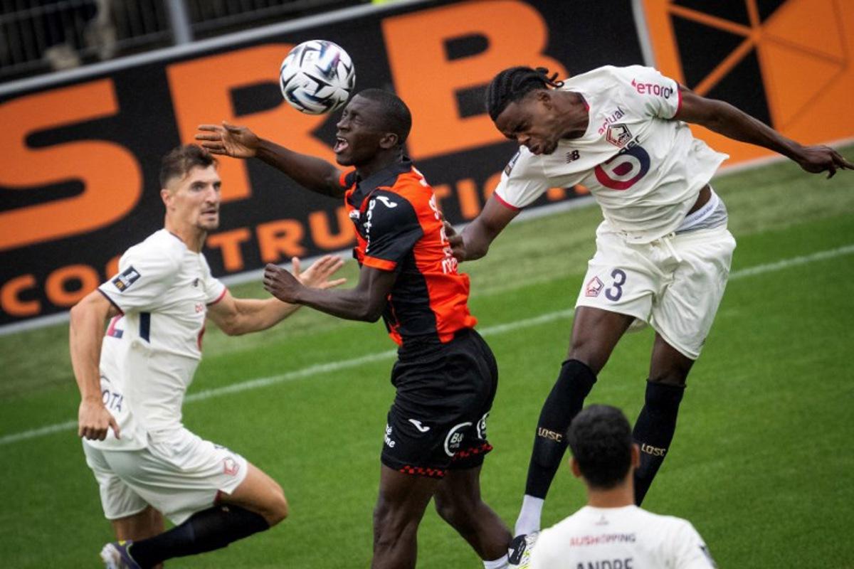 Lorient's Senegalese forward #28 Sambou Soumano (C) fights for the ball with Lille's Belgian defender #03 Nathan Ngoy (R) during the French L1 football match between FC Lorient and lille OSC at Yves-Allainmat stadium in Lorient, western France on August 30, 2025.   Loic VENANCE / AFP