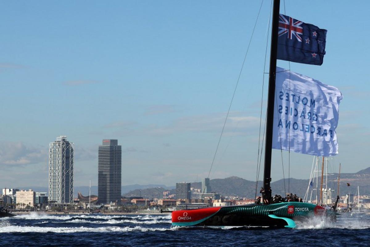 Members of the crew of defender Emirates Team New Zealand hoist a flagf reading in Catalan "Thanks a lot Barcelona" as they celebrate winning the Louis Vuitton 37th America's Cup Match, in Barcelona on October 19, 2024.  LLUIS GENE / AFP