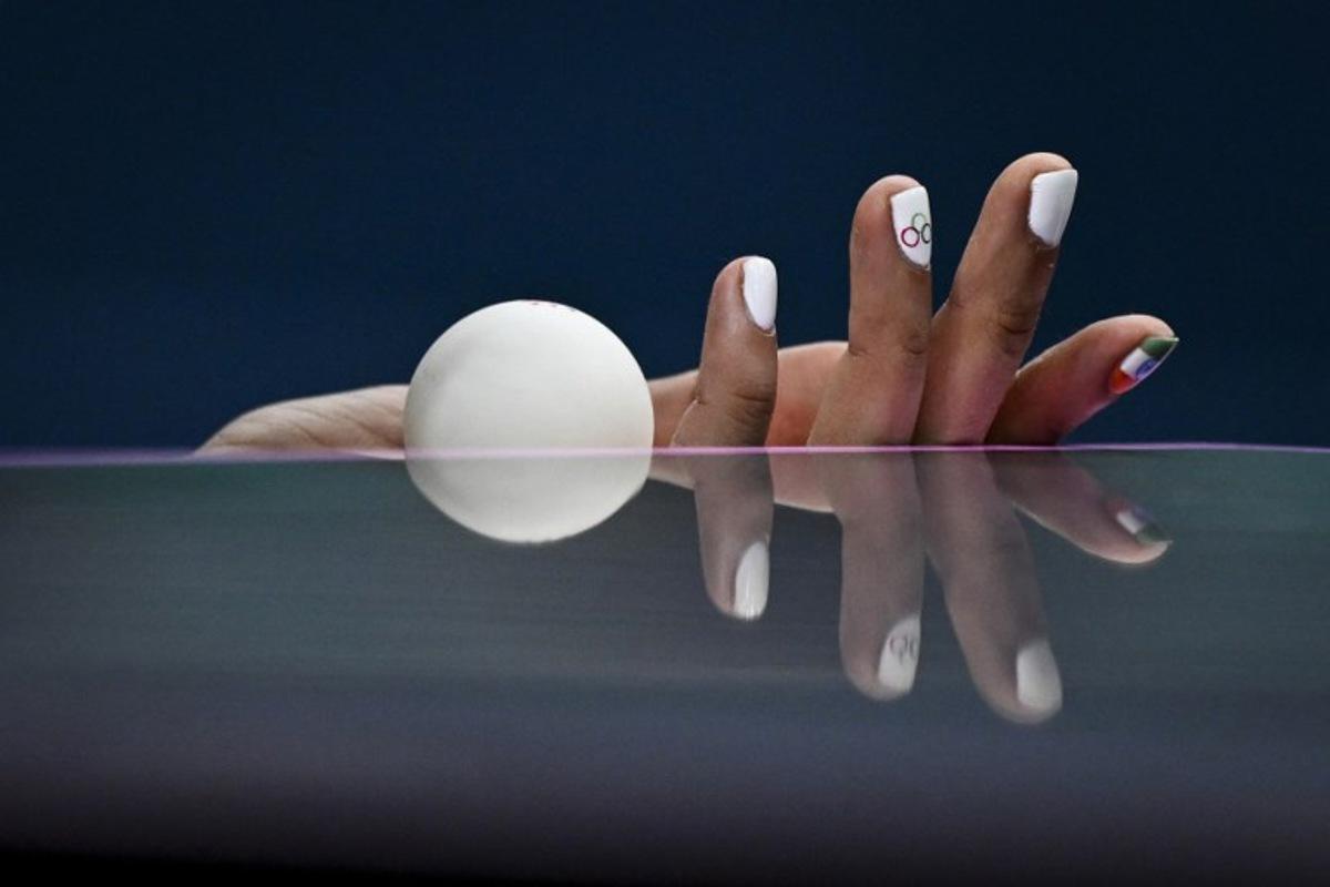 the hand and nails decorated with the Olympic Rings and the Indian flag is pictured as India's Manika Batra holds the ball prior to serve against France's Prithika Pavade during their women's table tennis singles round of 32 at the Paris 2024 Olympic Games at the South Paris Arena in Paris on July 29, 2024.  WANG Zhao / AFP