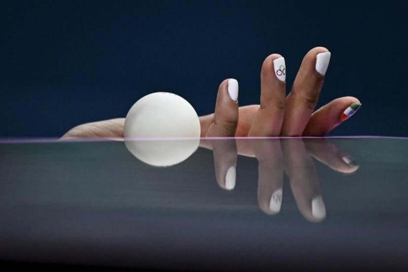the hand and nails decorated with the Olympic Rings and the Indian flag is pictured as India's Manika Batra holds the ball prior to serve against France's Prithika Pavade during their women's table tennis singles round of 32 at the Paris 2024 Olympic Games at the South Paris Arena in Paris on July 29, 2024.  WANG Zhao / AFP