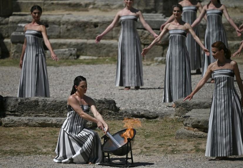Greek actress Mary Mina, in the role of the High Priestess, lights the torch during the rehearsal of the flame lighting ceremony for the Paris 2024 Olympic Games at the ancient temple of Hera on the Olympia archeological site, birthplace of the ancient Olympics in southern Greece, on April 15, 2024.  Valerie GACHE / AFP