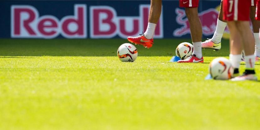Football players warm up in front of a "Red Bull" advertising banner on display at the stadium prior to the German second division Bundesliga football match between RB Leipzig and Karlsruher SC at the Red Bull Arena in Leipzig, eastern Germany, on May 8, 2016.  Leipzig won the match 2-0 and will be promoted to the first division Bundesliga next season. Robert MICHAEL / AFP