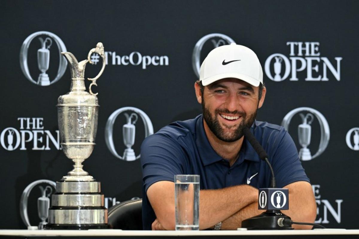 US golfer Scottie Scheffler with the Claret Jug, the trophy for the Champion golfer of the year beside him, holds a press conference after his victory in the 153rd Open Championship at Royal Portrush golf club in Northern Ireland on July 20, 2025. Scottie Scheffler romped to a magnificent four-shot victory to seal his first British Open title at Royal Portrush on Sunday, notching his fourth major success. The world number one eased to a three-under par final round of 68, finishing on 17-under for the tournament after shooting in the 60s on all four days.  ANDY BUCHANAN / AFP