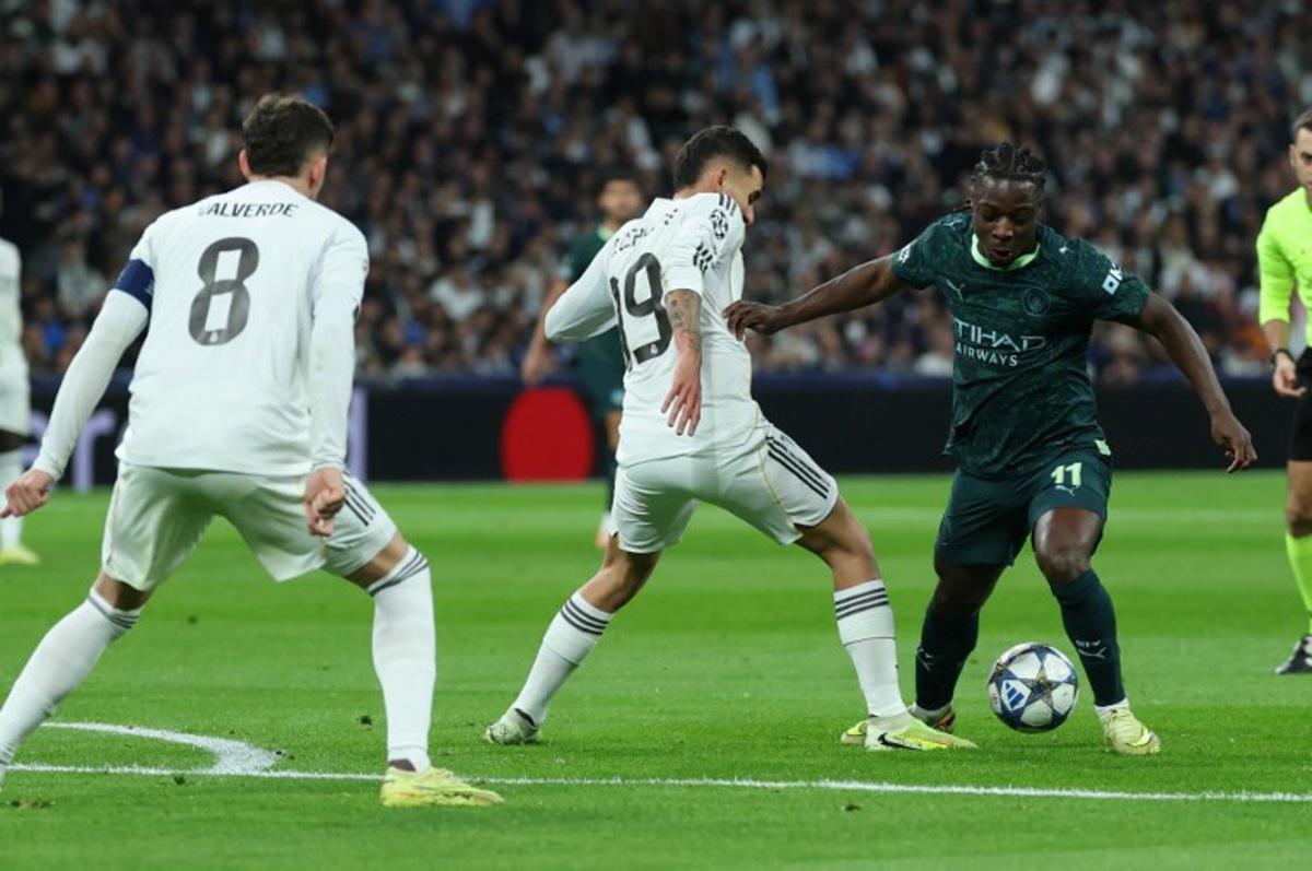 Manchester City's Belgian midfielder #11 Jeremy Doku (R) vies for the ball with Real Madrid's Spanish midfielder #19 Dani Ceballos during the UEFA Champions League league phase day 6 football match between Real Madrid CF and Manchester City at Santiago Bernabeu Stadium in Madrid on December 10, 2025.  Thomas COEX / AFP