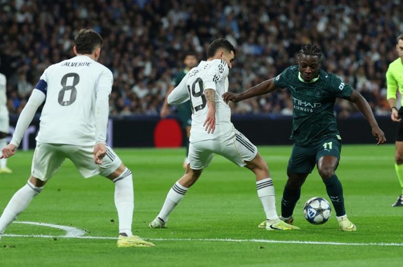 Manchester City's Belgian midfielder #11 Jeremy Doku (R) vies for the ball with Real Madrid's Spanish midfielder #19 Dani Ceballos during the UEFA Champions League league phase day 6 football match between Real Madrid CF and Manchester City at Santiago Bernabeu Stadium in Madrid on December 10, 2025.  Thomas COEX / AFP