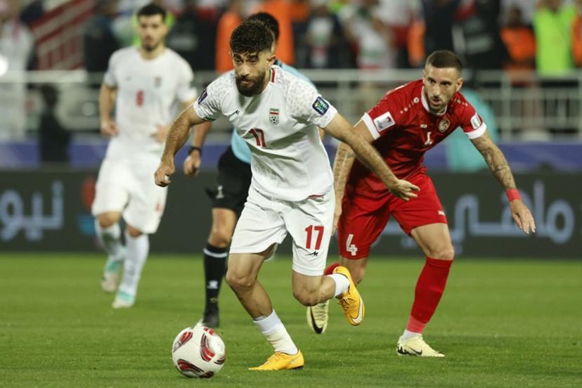Iran's midfielder #17 Ali Gholizadeh runs with the ball past Syria's midfielder #04 Ezequiel Ham during the Qatar 2023 AFC Asian Cup football match between Iran and Syria at the Abdullah bin Khalifa Stadium in Doha on January 31, 2024.  KARIM JAAFAR / AFP