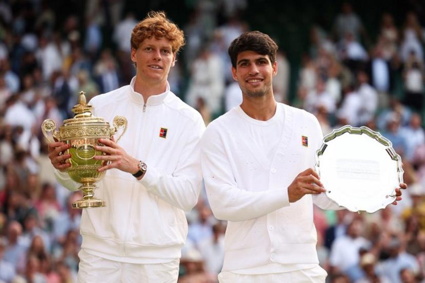 Italy's Jannik Sinner (L) holding the winner's trophy and second-placed Spain's Carlos Alcaraz pose for pictures during the price ceremony at the end of their men's singles final tennis match on the fourteenth day of the 2025 Wimbledon Championships at The All England Lawn Tennis and Croquet Club in Wimbledon, southwest London, on July 13, 2025.  HENRY NICHOLLS / AFP
