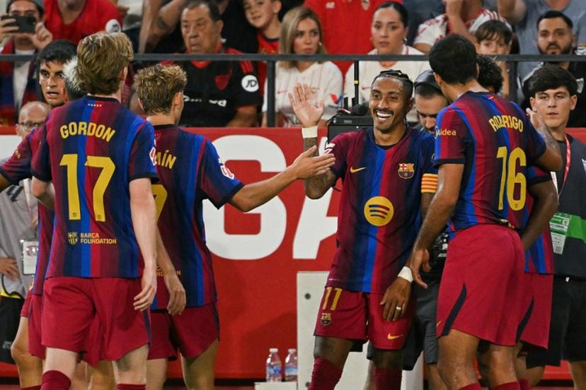 Barcelona's Brazilian forward #11 Raphinha (C) celebrates with teammates after scoring his team's third goal during the Spanish league football match between Sevilla FC and FC Barcelona at the Ramon Sanchez Pizjuan stadium in Seville on September 19, 2026.  JORGE GUERRERO / AFP