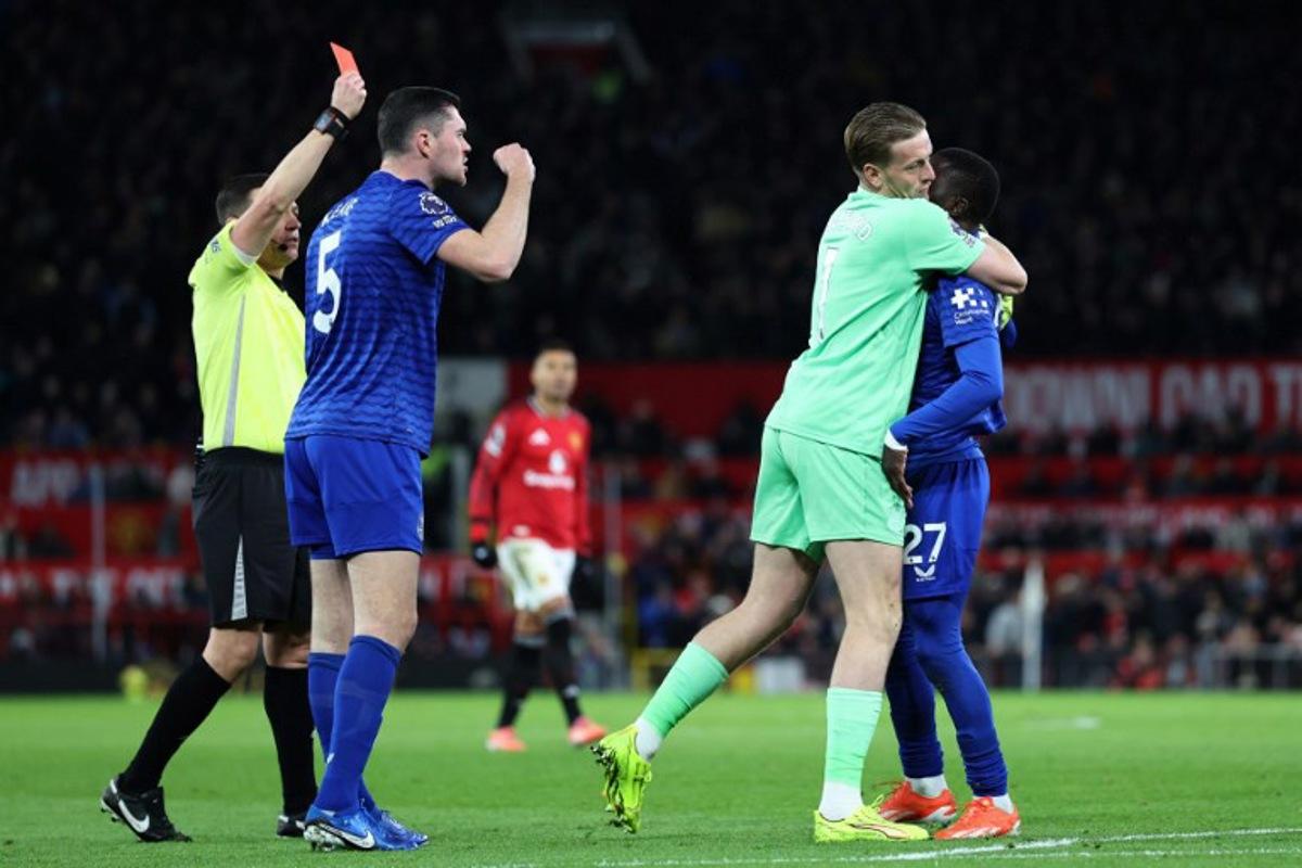 Everton's English goalkeeper #01 Jordan Pickford (2R) separates Everton's Senegalese midfielder #27 Idrissa Gueye (R) from Everton's English defender #05 Michael Keane (2L) as English referee Tony Harrington (L) shows a red card to Gueye during the English Premier League football match between Manchester United and Everton at Old Trafford in Manchester, north west England, on November 24, 2025.  Darren Staples / AFP