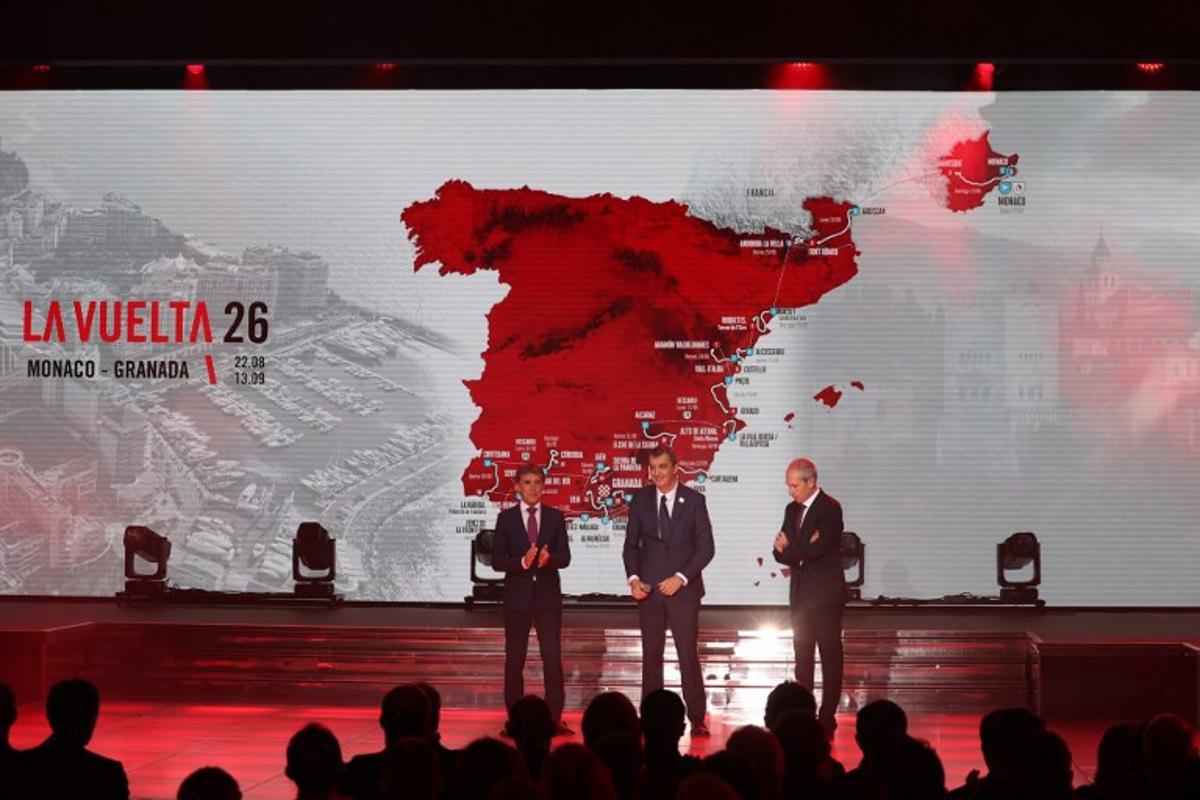 Race director of La Vuelta, Javier Guillen (C), Sports journalist Carlos de Andres (R) and Spanish former cyclist Pedro Delgado react as the race itinerary is displayed on a screen during the presentation of the 81th edition of 'La Vuelta' cycling tour of Spain, in Monaco on December 17, 2025. The 2026 Vuelta a Espana will start with a time-trial in Monaco and finish in Granada, after organisers on December 17, 2025 unveiled what they say will be one of the most difficult routes in the race's history. Valery HACHE / AFP