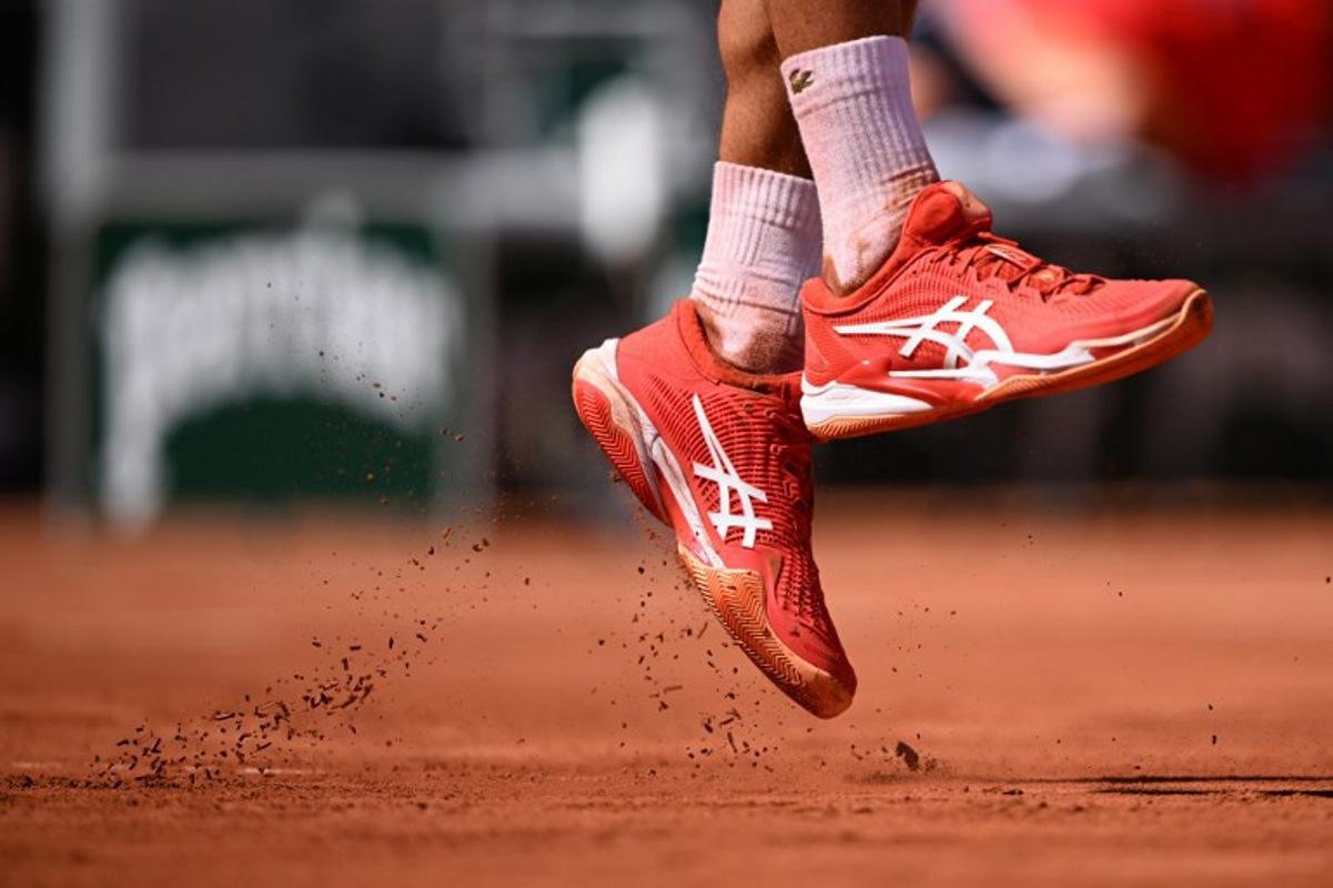 Clay fall as Serbia's Novak Djokovic serves to US Aleksandar Kovacevic during their men's singles match on day two of the Roland-Garros Open tennis tournament at the Court Philippe-Chatrier in Paris on May 29, 2023.  Emmanuel DUNAND / AFP