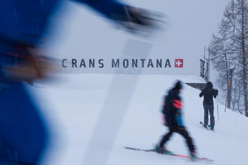 Skiers ski past a logo of Crans Montana on the sidelines of the women's downhill race part of the FIS Alpine Ski World Cup 2025-2026, in Crans Montana, Switzerland, on January 30, 2026.  Maxime Schmid / AFP