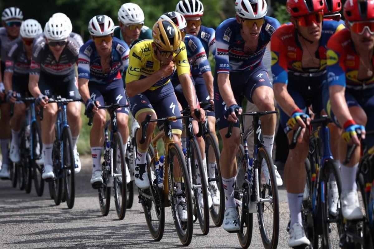 Soudal Quick-Step's Belgian rider Remco Evenepoel (C) wearing the overall leader's yellow jersey cycles with the pack during the 5th stage of the 77th edition of the Criterium du Dauphine cycling race, 183 km between Saint-Priest and Mâcon, on June 12, 2025.  Anne-Christine POUJOULAT / AFP