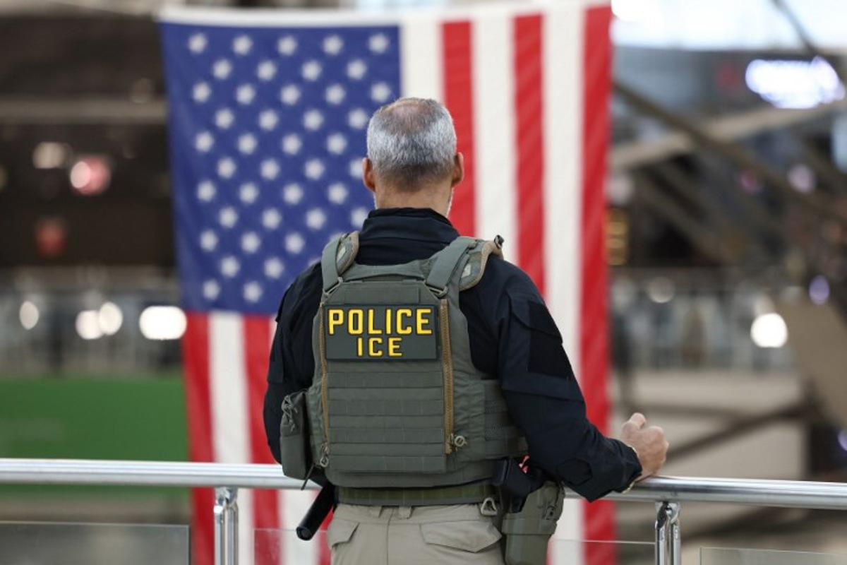 A US Immigrations and Customs Enforcement (ICE) stands watch at a security checkpoint at John F. Kennedy International Airport in New York, on March 23, 2026. Immigration agents will be deployed in US airports beginning Monday, aiming to alleviate soaring congestion at security screenings amid a weeks-long budget standoff over President Donald Trump's mass deportation drive, officials said. CHARLY TRIBALLEAU / AFP