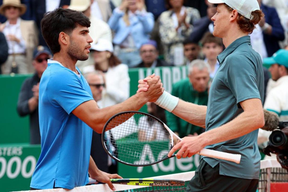 Italy's Jannik Sinner (R) shakes hands with Spain's Carlos Alcaraz after winning the Monte Carlo ATP Masters Series Tournament final tennis match on Court Rainier III at the Monte-Carlo Country Club in Roquebrune-Cap-Martin, south-eastern France on April 12, 2026.  Valery HACHE / AFP
