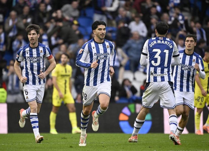 Real Sociedad's Spanish defender #18 Carlos Soler (C) celebrates scoring his team's first goal during the Spanish league football match between Real Sociedad and Villarreal CF at Anoeta Stadium in San Sebastian on November 30, 2025.  ANDER GILLENEA / AFP