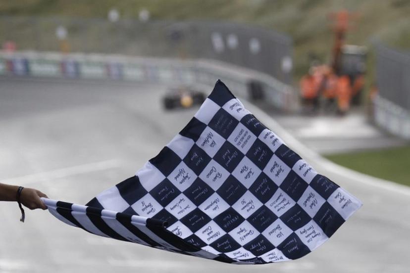 A person waves a finish flag as Red Bull Racing's Dutch driver Max Verstappen drives to win the Dutch Formula One Grand Prix race at The Circuit Zandvoort, in Zandvoort on August 27, 2023.  SIMON WOHLFAHRT / POOL / AFP