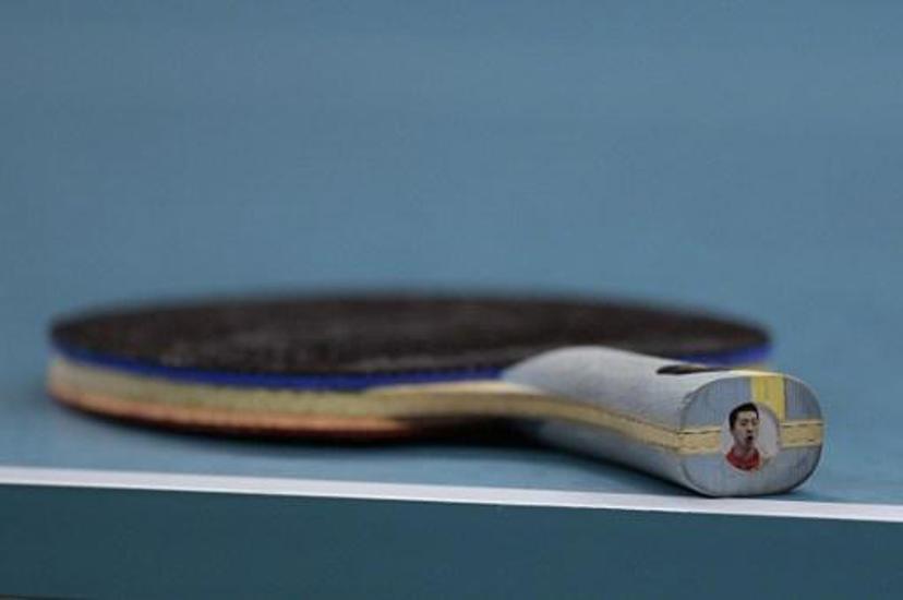China's Ma Long's racket is seen on the table with his own picture on the end in the men's team gold medal table tennis match against Japan's Maharu Yoshimura at the Riocentro venue during the Rio 2016 Olympic Games in Rio de Janeiro on August 17, 2016. 
Juan Mabromata / AFP
