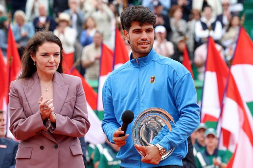 Second placed Spain's Carlos Alcaraz (R) delivers a speech flanked by President of the Monegasque Federation, the Rolex Masters 1000 and the Monte-Carlo Country Club Melanie de Massy during the podium ceremony and following the Monte Carlo ATP Masters Series Tournament final tennis match on Court Rainier III at the Monte-Carlo Country Club in Roquebrune-Cap-Martin, south-eastern France on April 12, 2026.  Valery HACHE / AFP