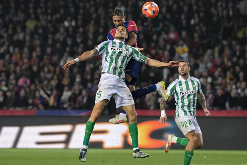 Real Betis' Spanish defender #05 Marc Bartra (front) and Barcelona's Brazilian forward #11 Raphinha go for a header during the Spanish league football match between FC Barcelona and Real Betis at the Estadi Olimpic Lluis Companys in Barcelona, on April 5, 2025.  Josep LAGO / AFP