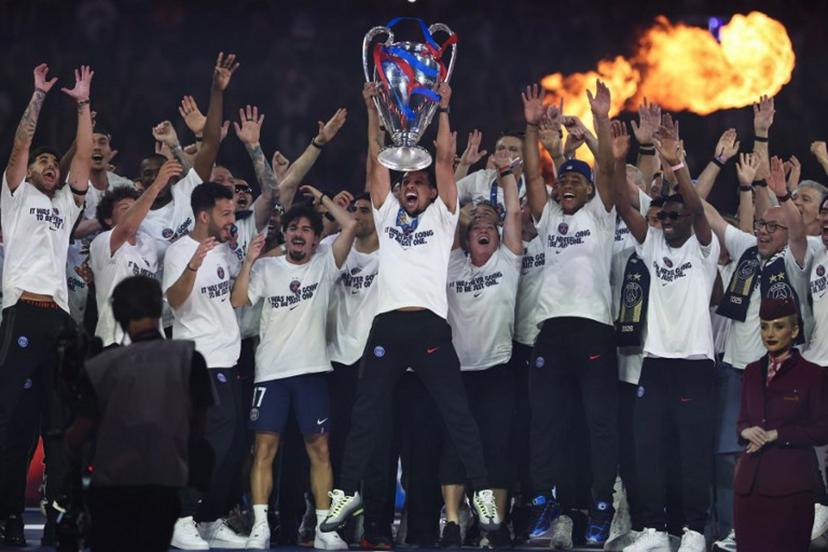 Paris Saint-Germain's Brazilian defender #05 Marquinhos (C) holds the trophy surrounded by teamamtes at Parc des Princes stadium, in Paris on May 31, 2026, during a special event organised to celebrate with supporters their victory over Arsenal FC in the UEFA Champions League final. Paris Saint-Germain (PSG) claimed back-to-back Champions League triumphs with a 4-3 shoot-out win over Arsenal following a 1-1 draw after extra time on May 30, 2026. FRANCK FIFE / POOL / AFP