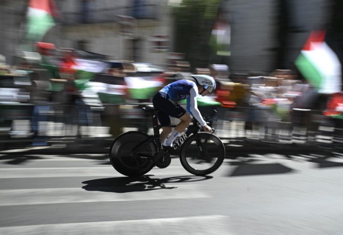Pro-Palestinians protesters wave Palestinian flags as Team Israel Premier Tech 's British rider Jake Stewart competes during the 18th stage of the Vuelta a Espana, a 26 km race against the clock between Valladolid and Valladolid, on September 11, 2025.    Miguel RIOPA / AFP