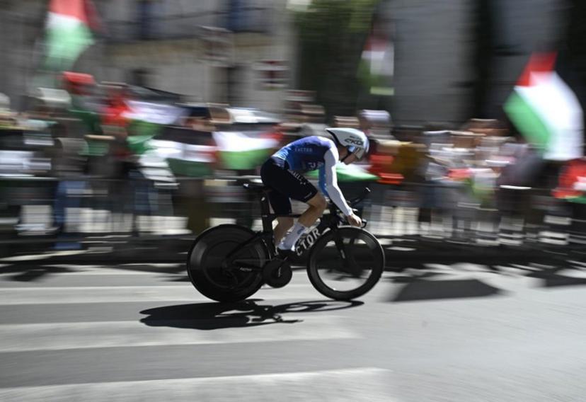 Pro-Palestinians protesters wave Palestinian flags as Team Israel Premier Tech 's British rider Jake Stewart competes during the 18th stage of the Vuelta a Espana, a 26 km race against the clock between Valladolid and Valladolid, on September 11, 2025.    Miguel RIOPA / AFP