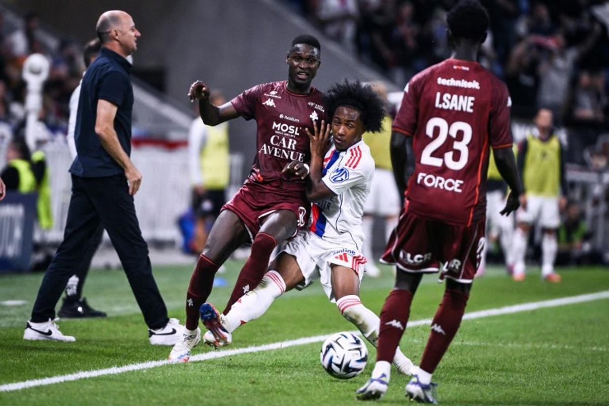 Lyon's Belgian forward #11 Malick Fofana (C) fights for the ball with Metz's Malian midfielder #08 Boubacar Traore (L) during the French L1 football match between Olympique Lyonnais (OL) and FC Metz at the Groupama Stadium in Decines-Charpieu, central-eastern France on August 23, 2025.  ARNAUD FINISTRE / AFP