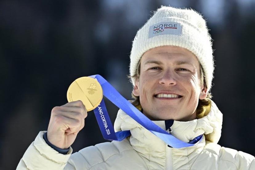Gold medallist Norway's Johannes Hoesflot Klaebo celebrates on the podium for the men's cross country 10km + 10km skiathlon event of the Milano Cortina 2026 Winter Olympics at Tesero Cross-Country Skiing Stadium in Lago di Tesero (Val di Fiemme), on February 8, 2026.  Tobias SCHWARZ / AFP