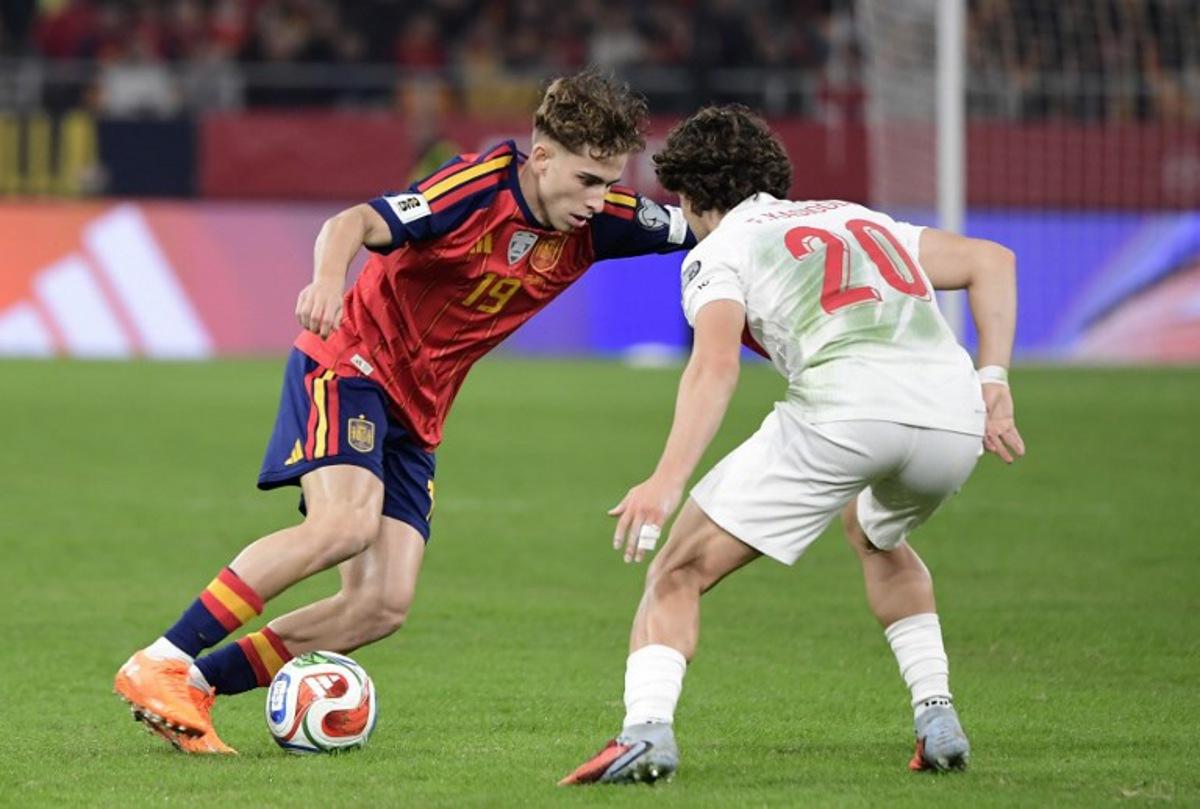 Spain's forward #19 Fermin Lopez fights for the ball with Turkey's defender #20 Ferdi Kadioglu during the FIFA World Cup 2026 European qualification Group E football match between Spain and Turkey at the Cartuja stadium in Seville on November 18, 2025.    CRISTINA QUICLER / AFP