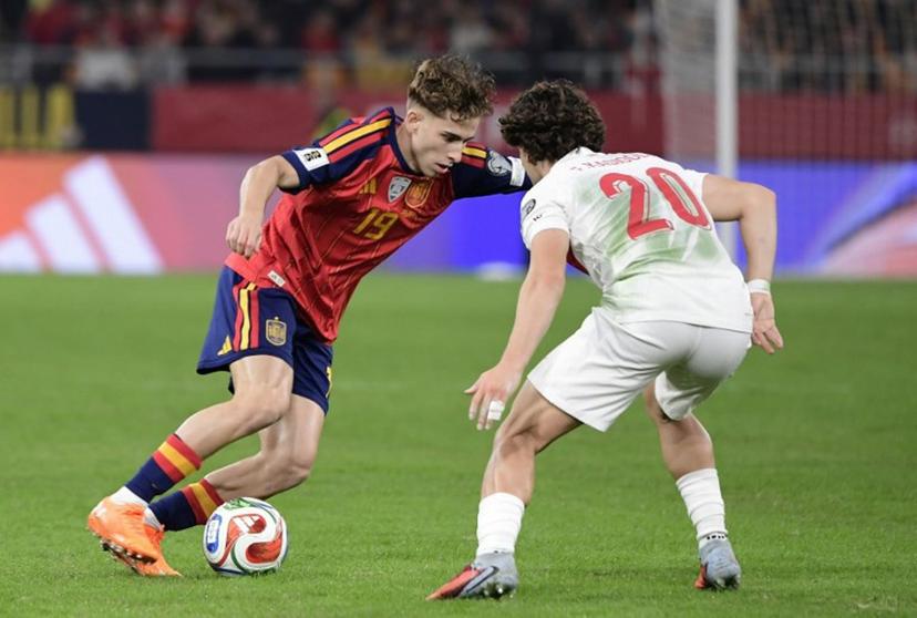 Spain's forward #19 Fermin Lopez fights for the ball with Turkey's defender #20 Ferdi Kadioglu during the FIFA World Cup 2026 European qualification Group E football match between Spain and Turkey at the Cartuja stadium in Seville on November 18, 2025.    CRISTINA QUICLER / AFP
