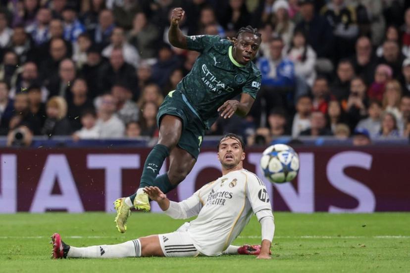 Manchester City's Belgian forward #11 Jeremy Doku shoots past Real Madrid's Spanish defender #35 Raul Asencio but fails to score during the UEFA Champions League league phase day 6 football match between Real Madrid CF and Manchester City at Santiago Bernabeu Stadium in Madrid on December 10, 2025.  Pierre-Philippe MARCOU / AFP