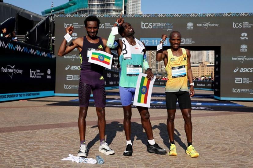 Winner Ethiopia's Addisu Gobena (C) reacts as he stands with second-placed Ethopia's Chimdessa Debele (L) and third-placed Lesotho's Tebello Ramakongoana after they crossed the finish line in the 2026 Sydney Marathon in Sydney on August 30, 2026.   DAVID GRAY / AFP
