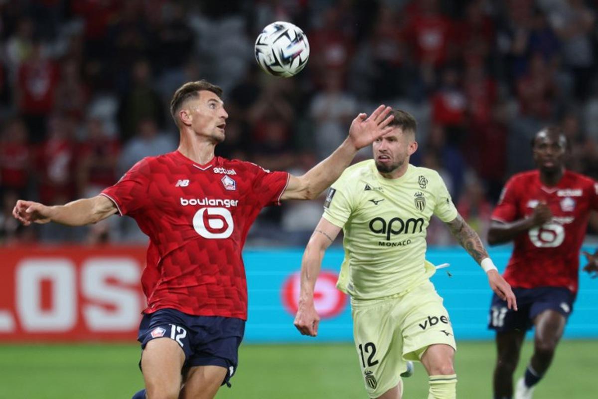 Lille's Belgian defender #12 Thomas Meunier (L) and Monaco's Brazilian midfielder #12 Caio Henrique fight for the ball  during the French L1 football match between Lille LOSC and AS Monaco at Stade Pierre-Mauroy in Villeneuve-d'Ascq, northern France on August 24, 2025.  FRANCOIS LO PRESTI / AFP