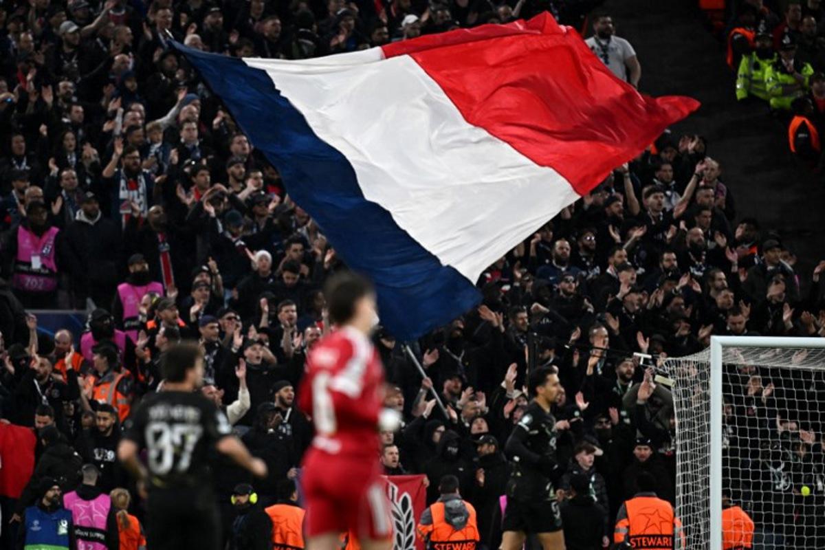 The French flag is flown in the stands by PSG fans during the UEFA Champions League quarter final, second-leg football match between Liverpool and Paris Saint-Germain at Anfield in Liverpool, north west England on April 14, 2026.  Paul ELLIS / AFP