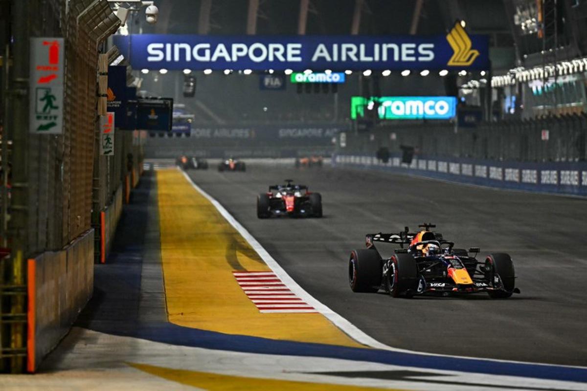 Red Bull Racing's Dutch driver Max Verstappen (R) drives in front of Ferrari's Monegasque driver Charles Leclerc during the Formula One Singapore Grand Prix at the Marina Bay Street Circuit in Singapore on October 11, 2026.  Lillian SUWANRUMPHA / AFP