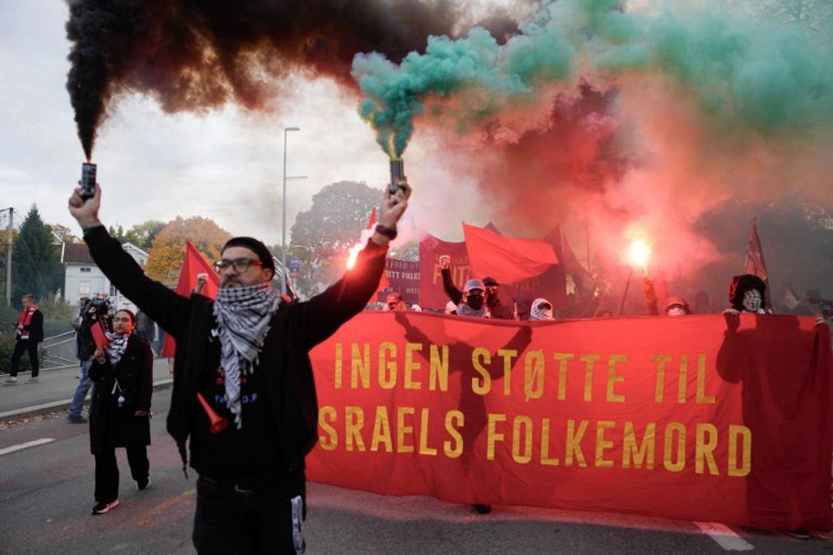 Protesters light flares as they demonstrate in solidarity with the Palestinian people and against Israel, close to the Ullevaal Stadium in Oslo, Norway, on October 11, 2025, prior to the 2026 World Cup qualifying football match between Norway and Israel.  Javad Parsa / NTB / AFP