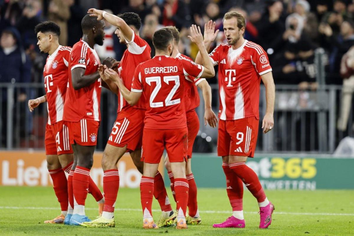 Bayern Munich's English forward #09 Harry Kane (R) celebrates scoring his team's second goal with Bayern Munich's Portuguese defender #22 Raphael Guerreiro and teammates during the UEFA Champions League football match between FC Bayern Munich and Club Brugge in Munich, southern Germany on October 22, 2025.  Alexandra BEIER / AFP