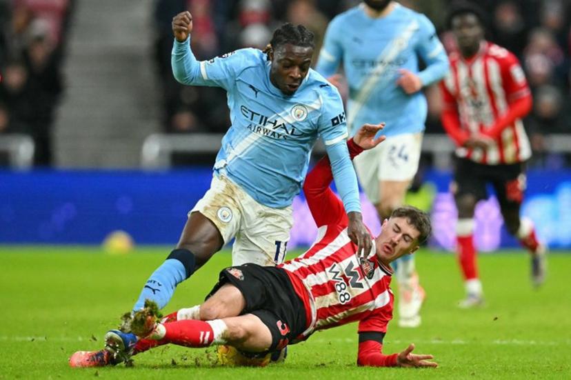 Sunderland's Northern Irish defender #32 Trai Hume (R) slides in to foul Manchester City's Belgian midfielder #11 Jeremy Doku (L) during the English Premier League football match between Sunderland and Manchester City at The Stadium of Light in Sunderland in north east England on January 1, 2026.  ANDY BUCHANAN / AFP